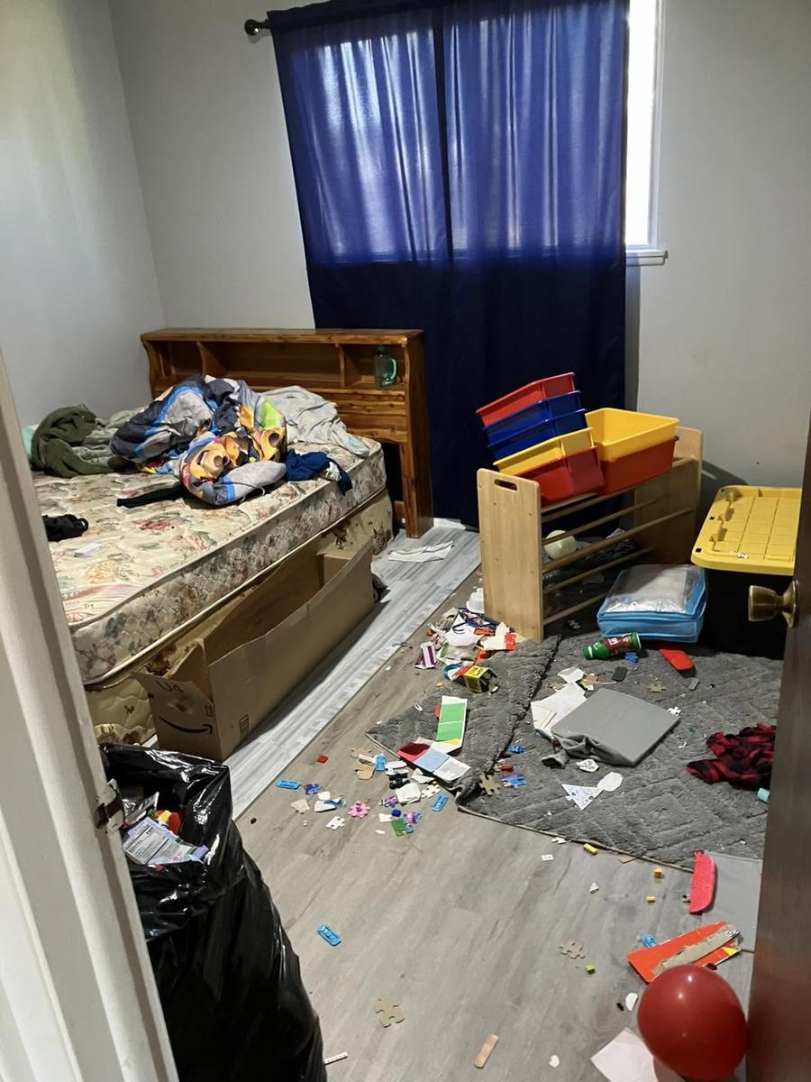 Before: a bedroom with toys, clothes and a trash bag across the floor