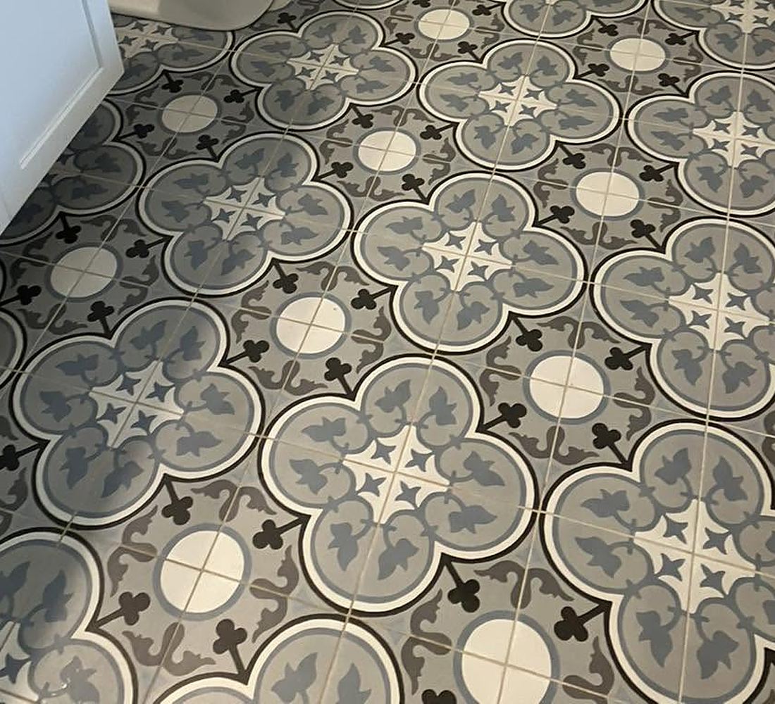 A bathroom floor of patterned grey and white tile, freshly cleaned