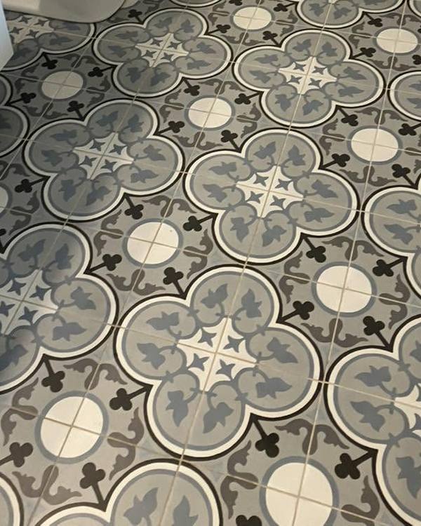 A bathroom with a patterned tile floor and a white vanity