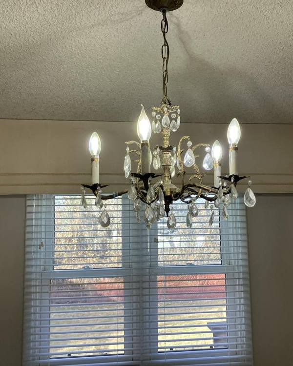 A dining room with a crystal chandelier and a bright window