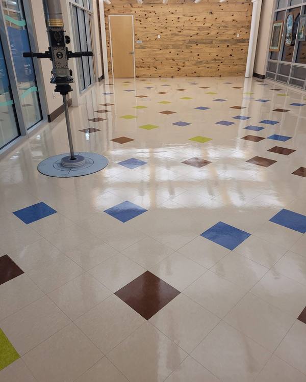 A wide hall of colored tile with a mirror shine