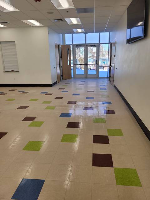 A long hallway with a glossy tile floor running to glass doors