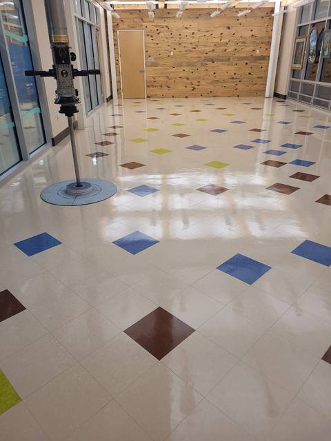 A wide hall of colored tile with a mirror shine