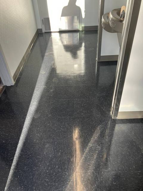 A dark speckled floor with a wet shine