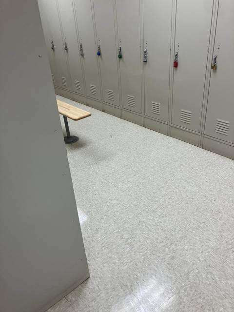 A row of grey lockers over a clean speckled floor