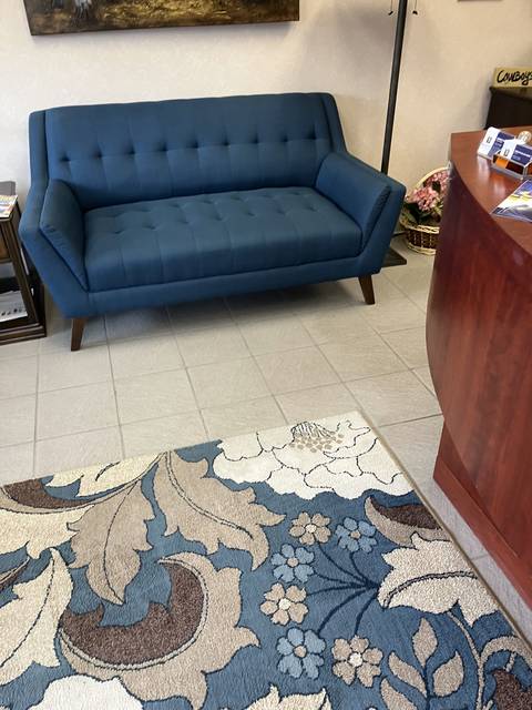 A lobby with a blue sofa and a patterned rug