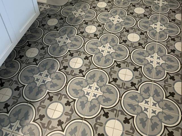 A bathroom with a patterned tile floor and a white vanity