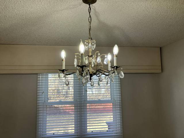 A dining room with a crystal chandelier and a bright window