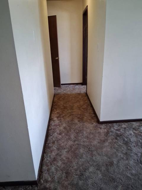 A carpeted hallway with the doors open