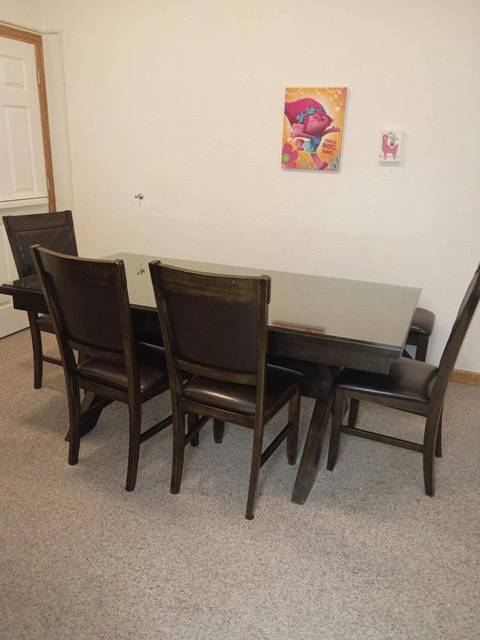 A dining table with dark chairs on a clean floor
