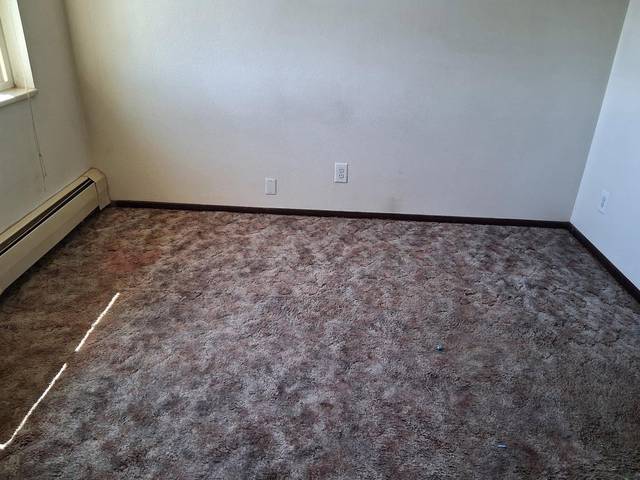 An empty carpeted room with clean baseboards